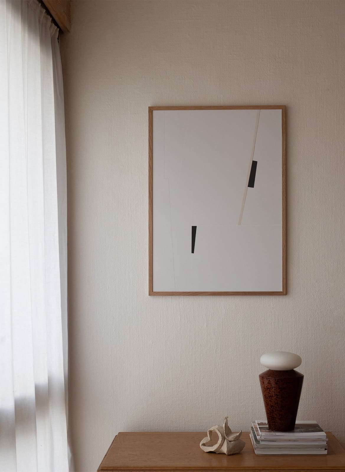 Framed minimalistic poster hanging above a table by atelier cph
