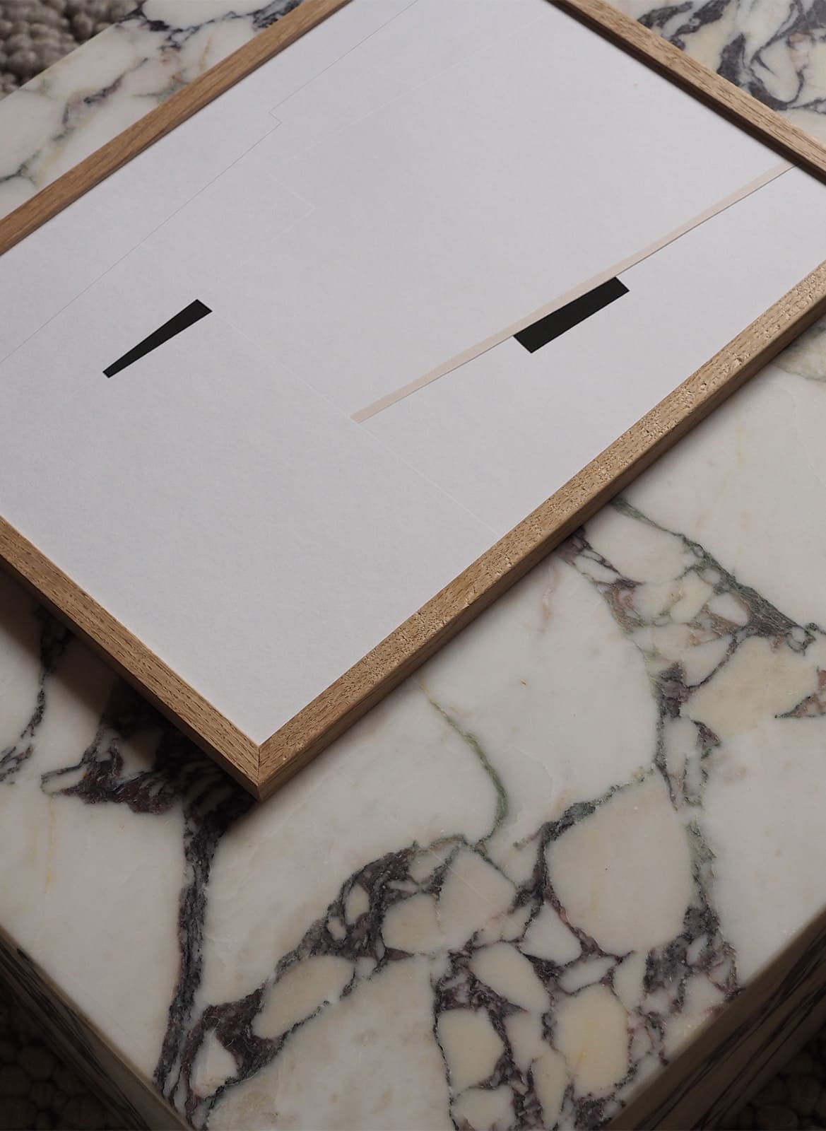 Framed minimalistic poster laying on a marble table by atelier cph