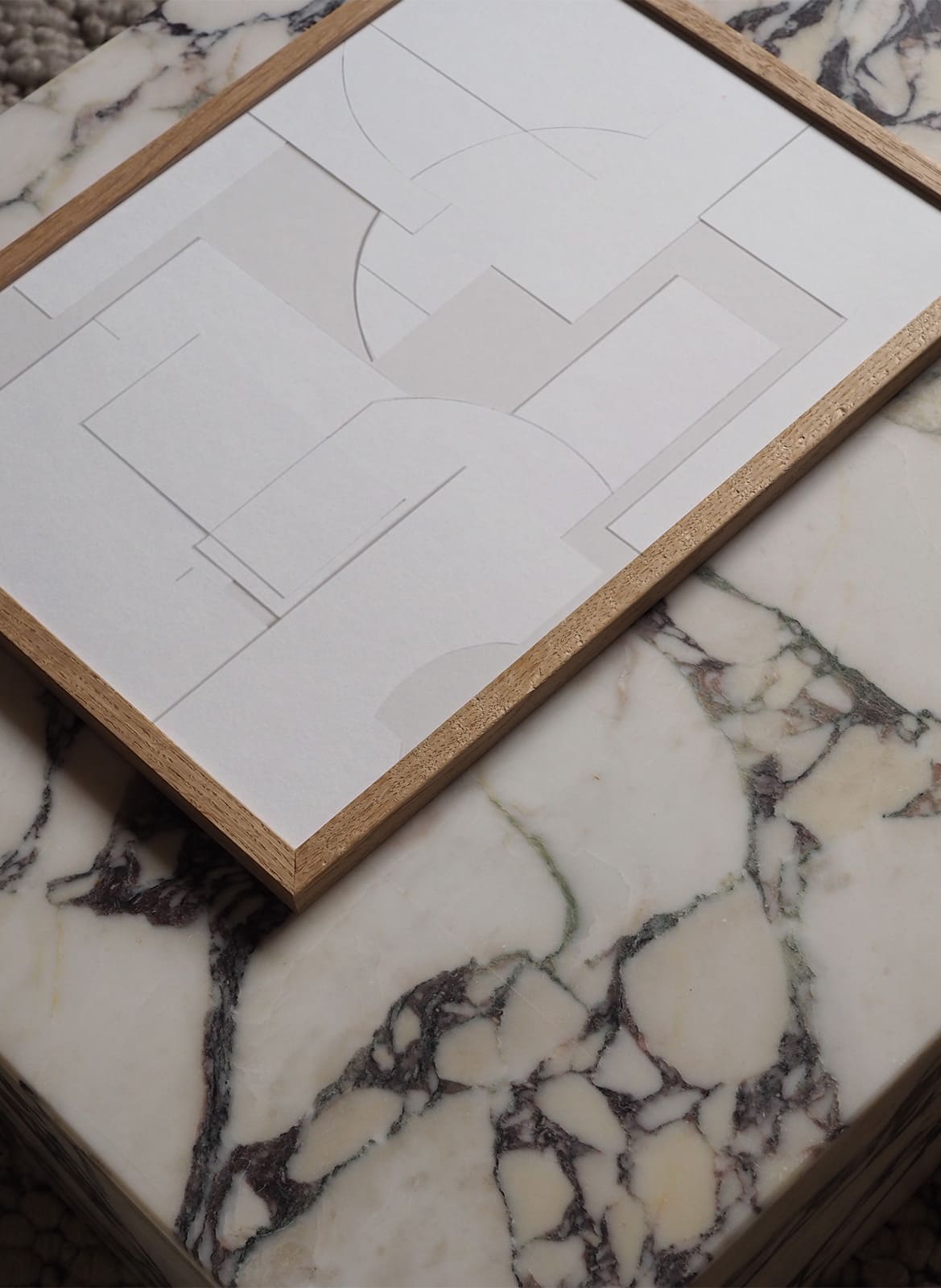 Framed white poster laying on a marble table by atelier cph