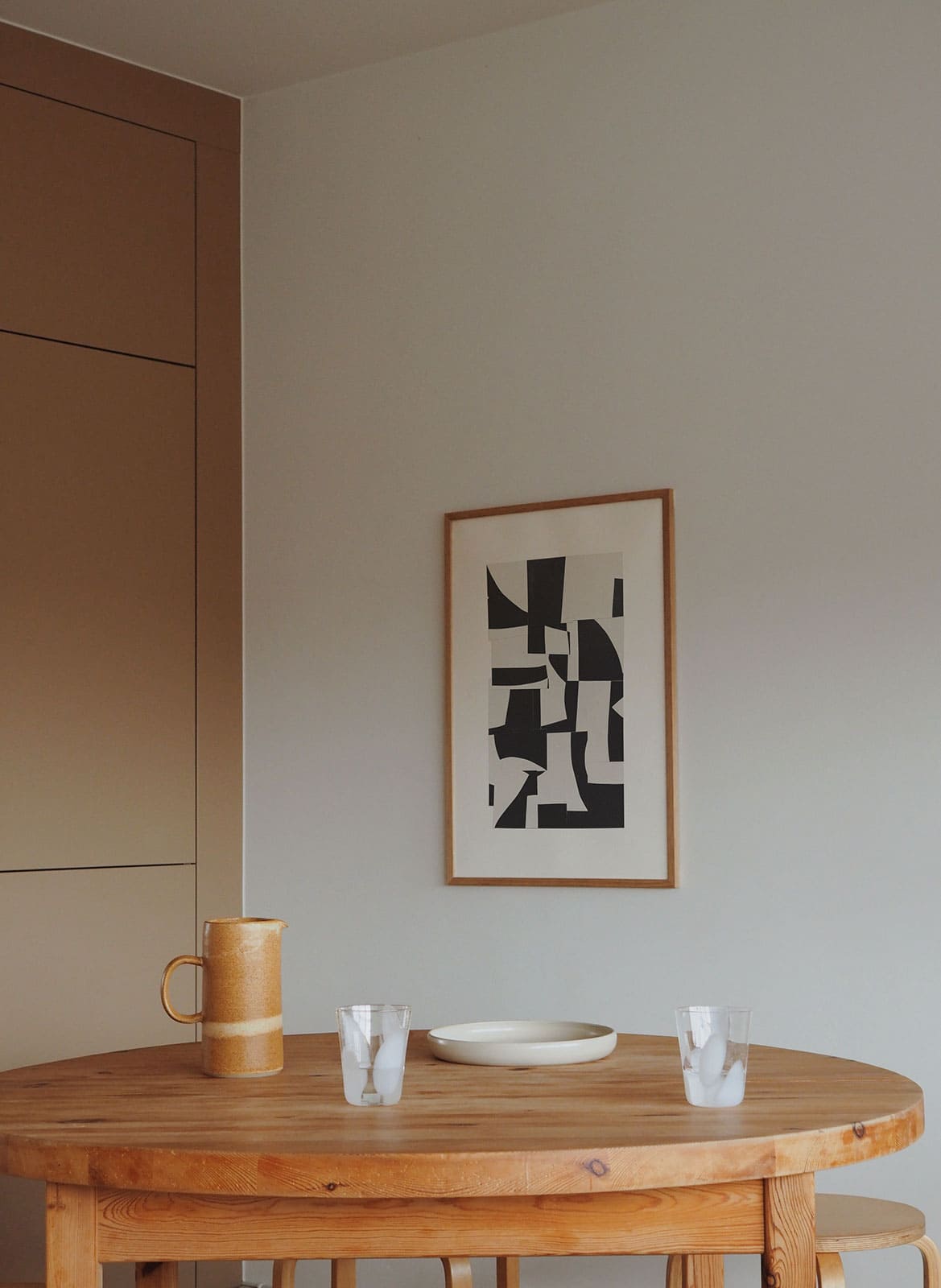 Framed black and white poster hanging above a kitchen table by atelier cph