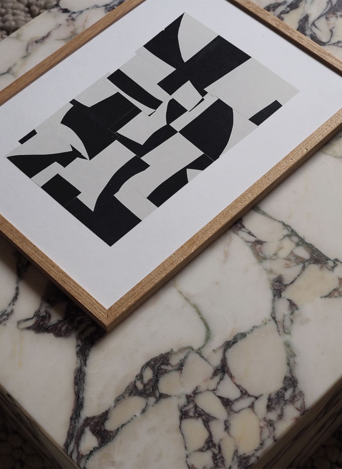 Framed black and white poster laying on a marble table by atelier cph