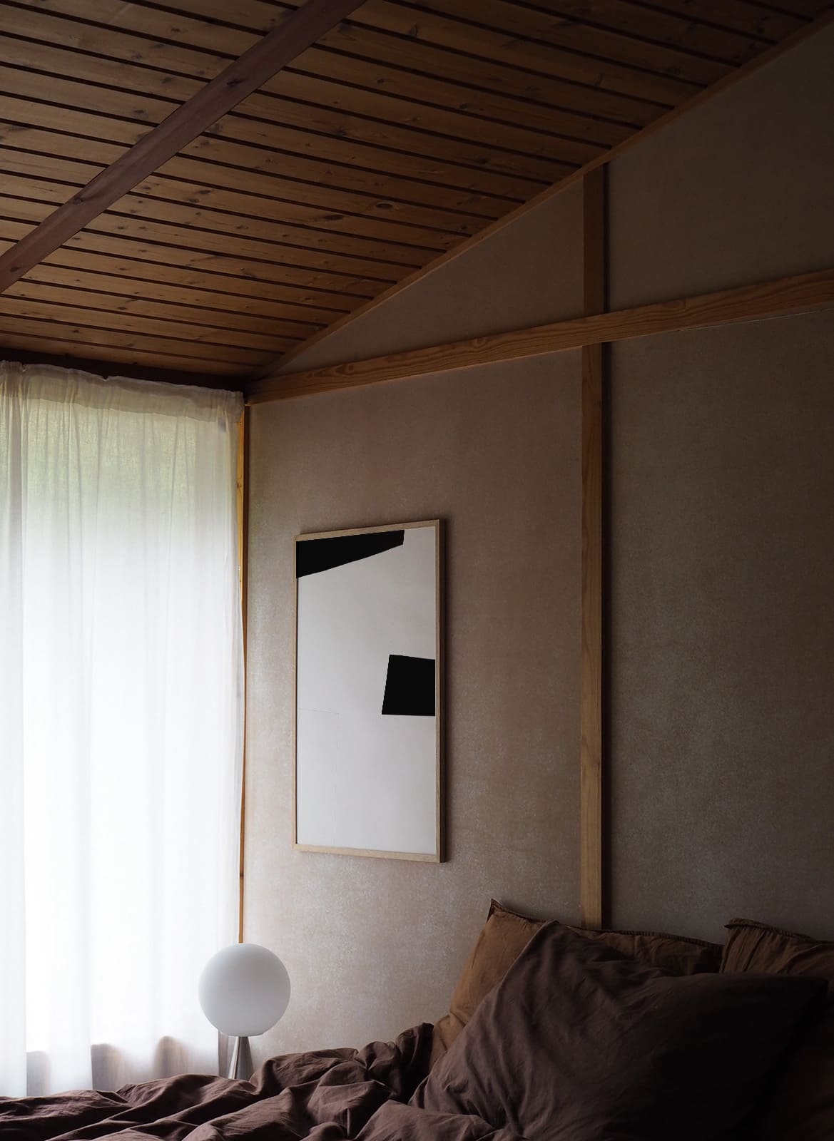 Framed minimalistic poster hanging above a bed by atelier cph