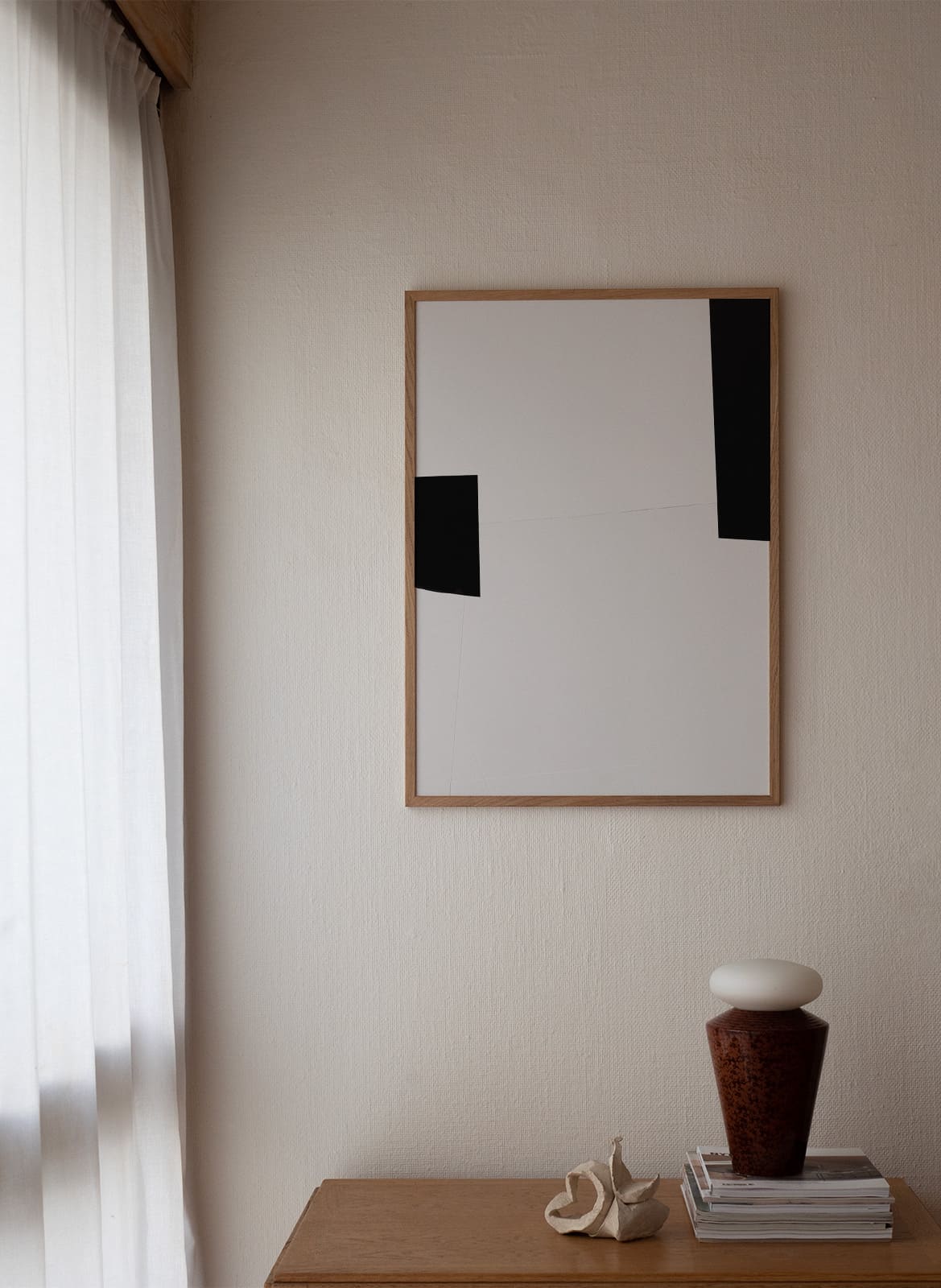 Framed minimalistic poster hanging above a table by atelier cph