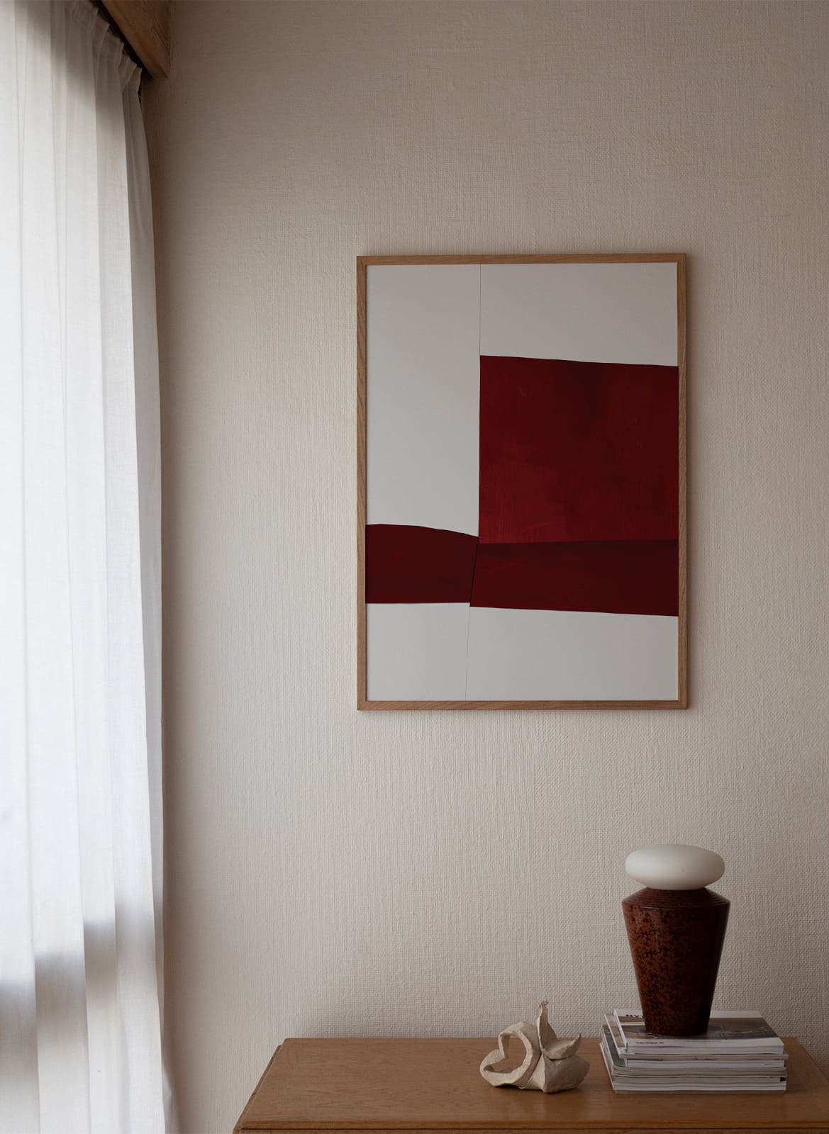 Framed minimalistic red poster hanging above a table by atelier cph