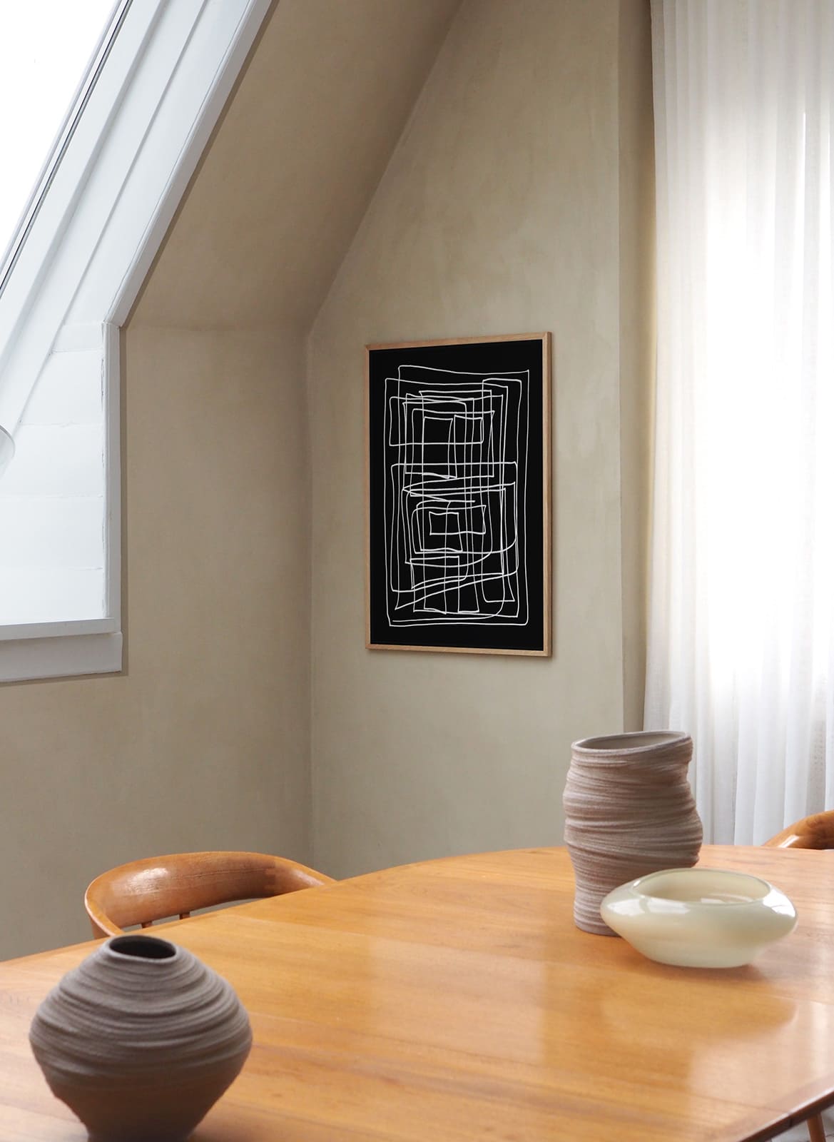 Framed black and white poster hanging above dining table by Atelier Cph