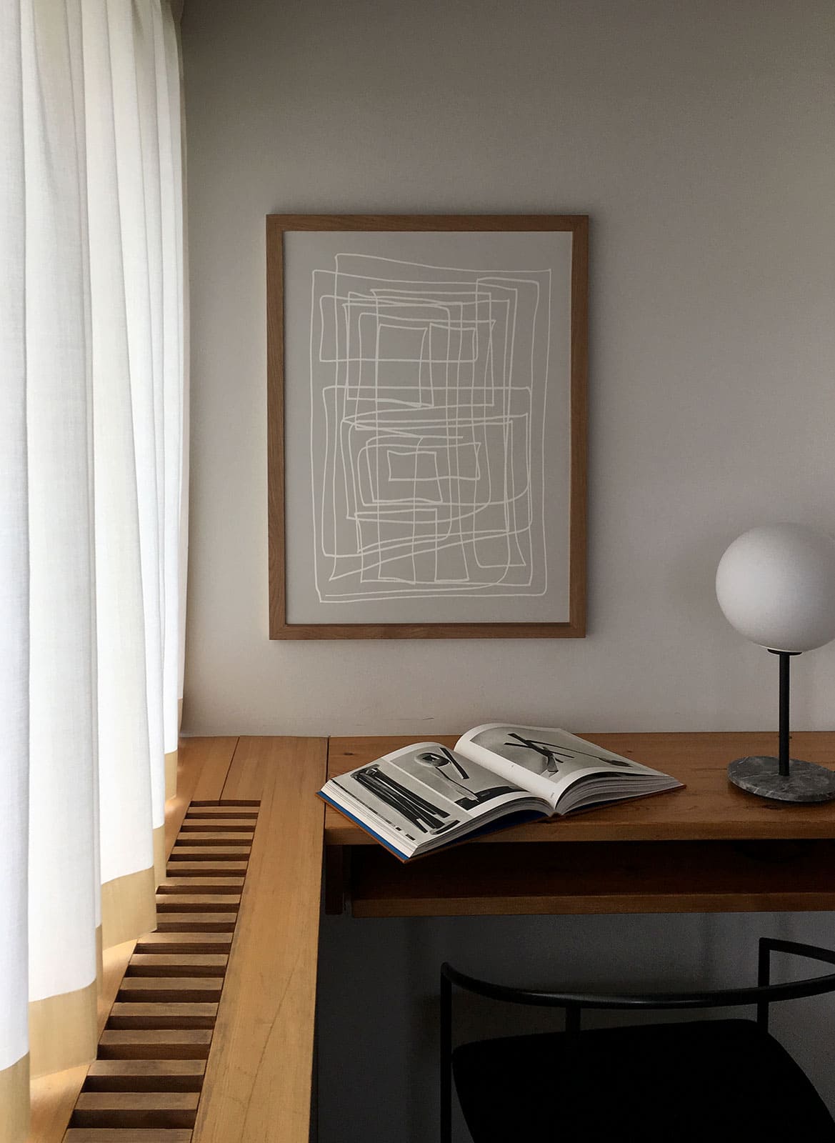   Framed minimalistic posters hanging above a desk/table by Atelier Cph
