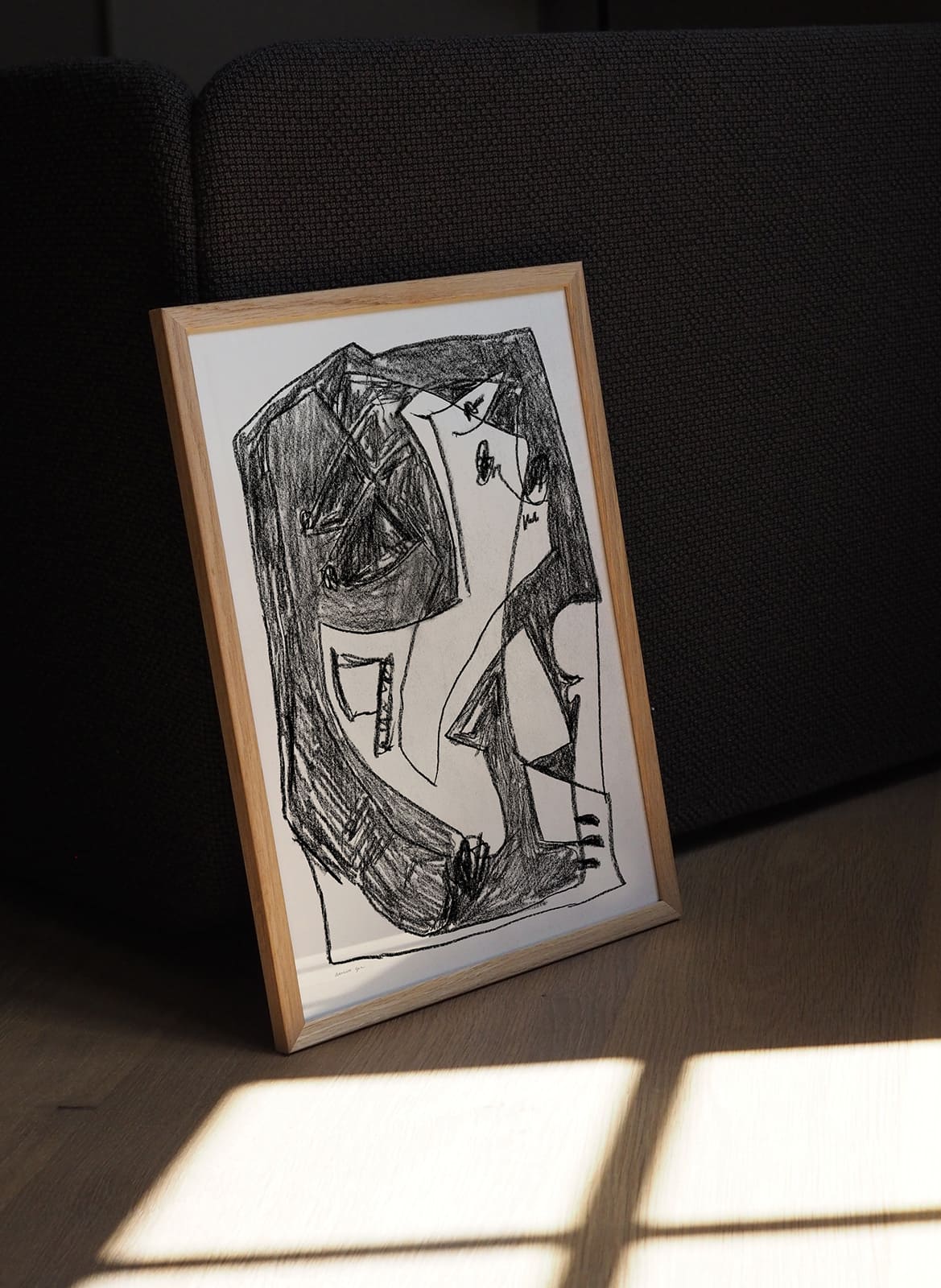 Framed minimalistic poster standing in a living room by Atelier Cph
