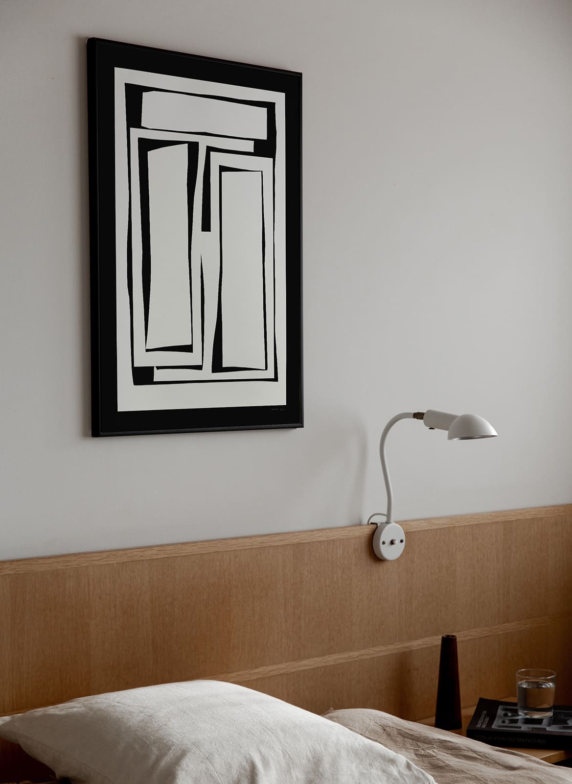 Framed minimalistic poster hanging above a bed by Atelier Cph
