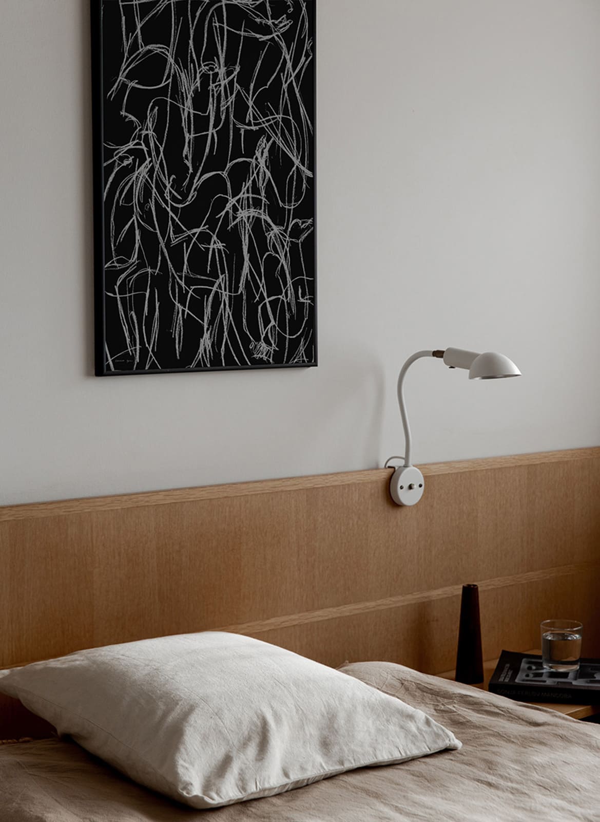 Framed minimalistic poster hanging above a bed by Atelier Cph
