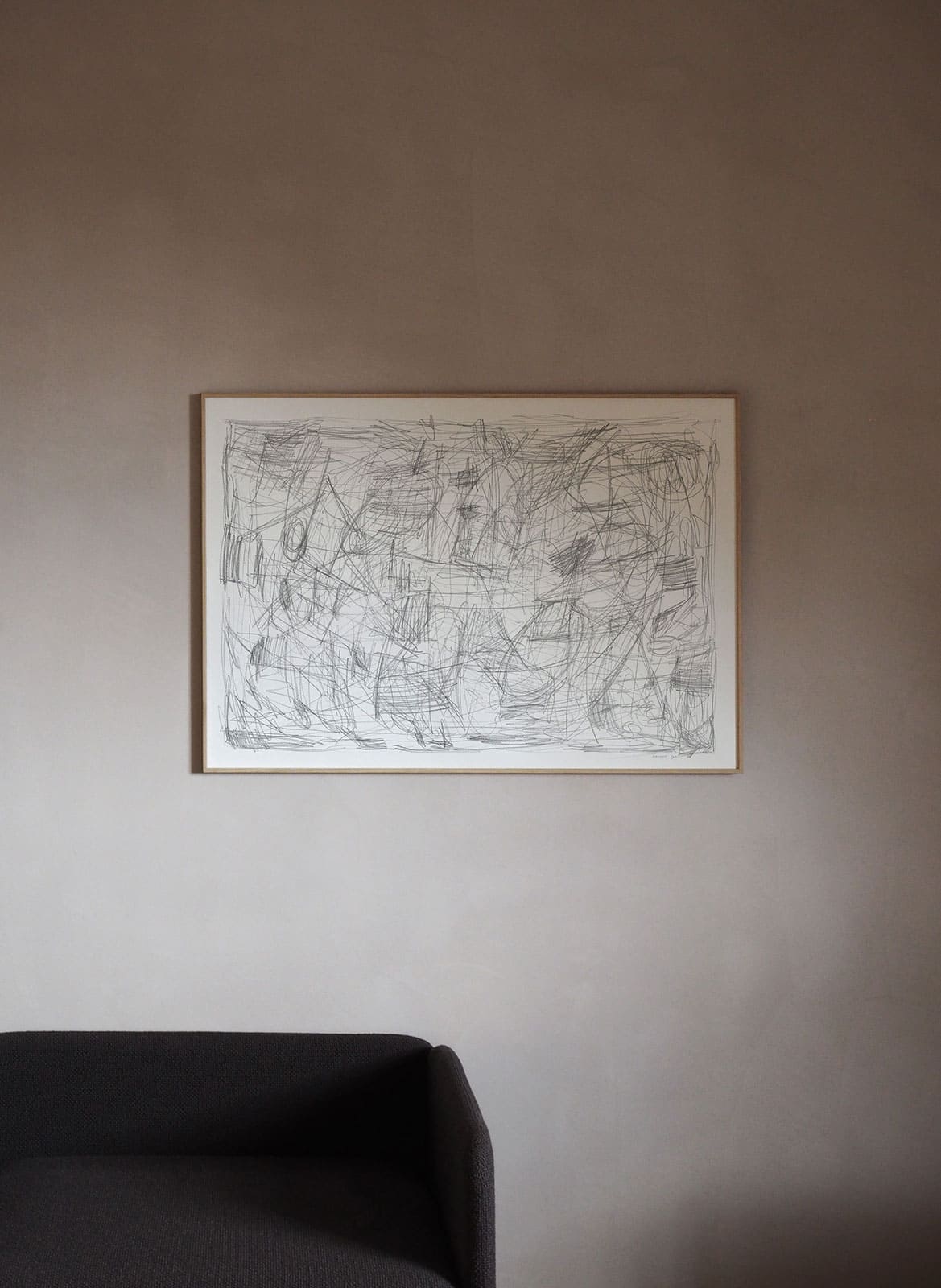 Framed pencil drawing poster hanging above couch by Atelier Cph