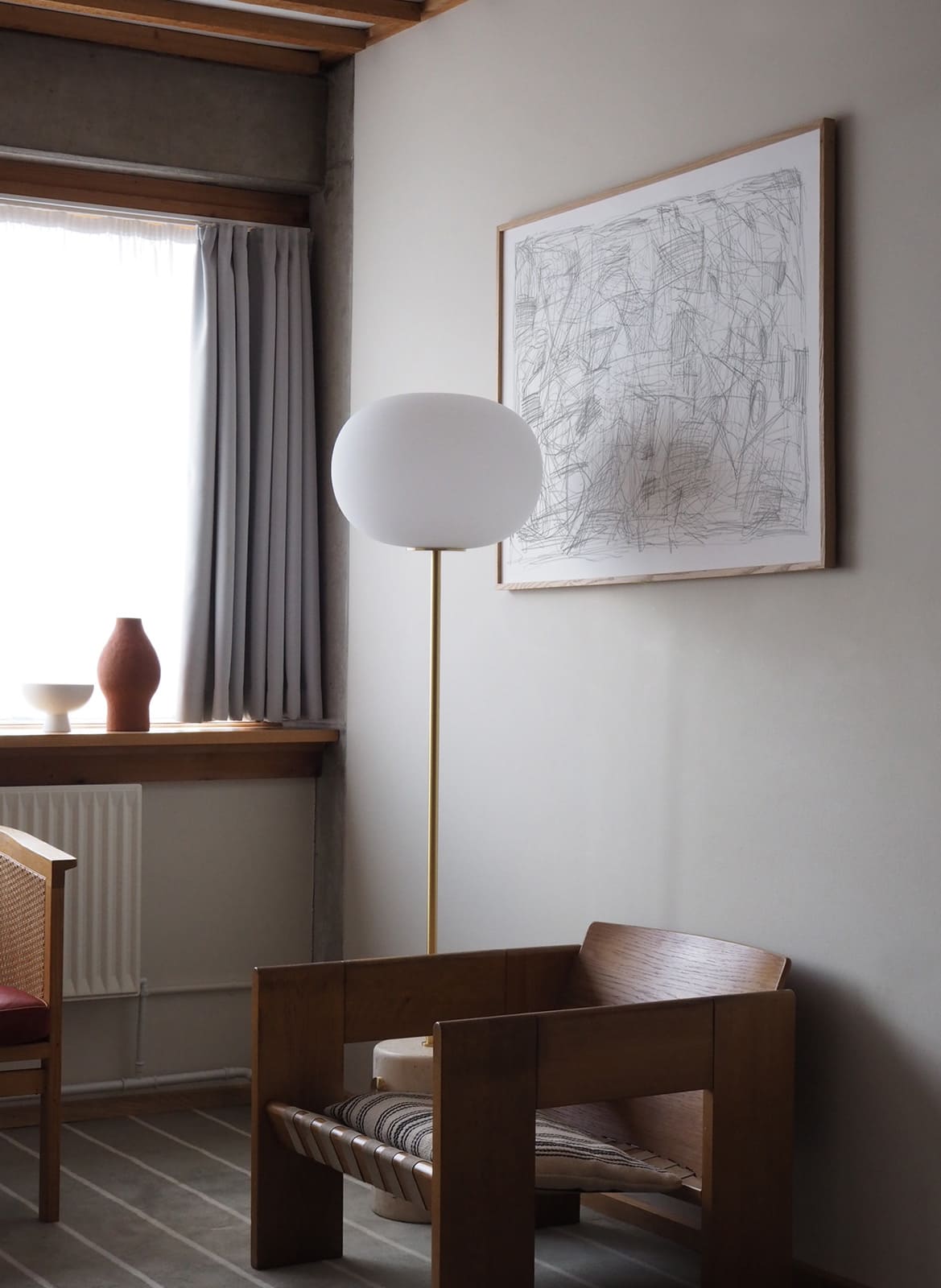 Framed pencil drawing poster hanging above a chair by Atelier Cph