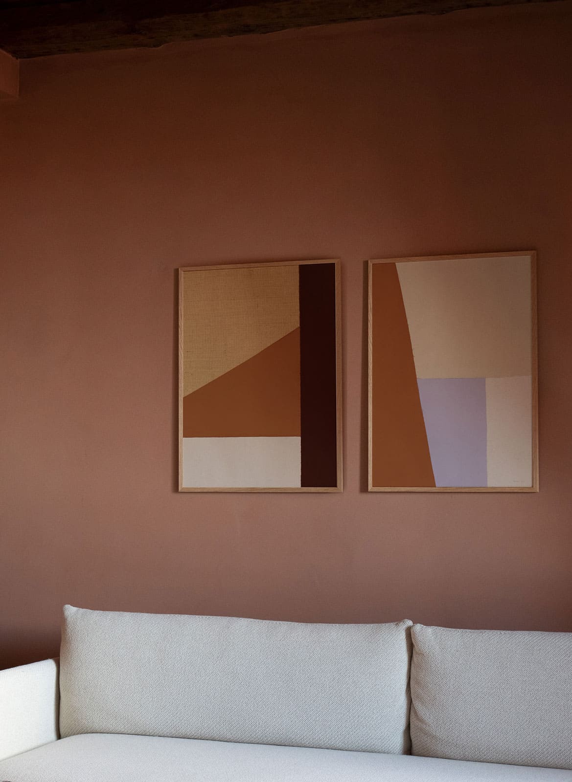 Framed colourful posters hanging above a couch by Atelier Cph