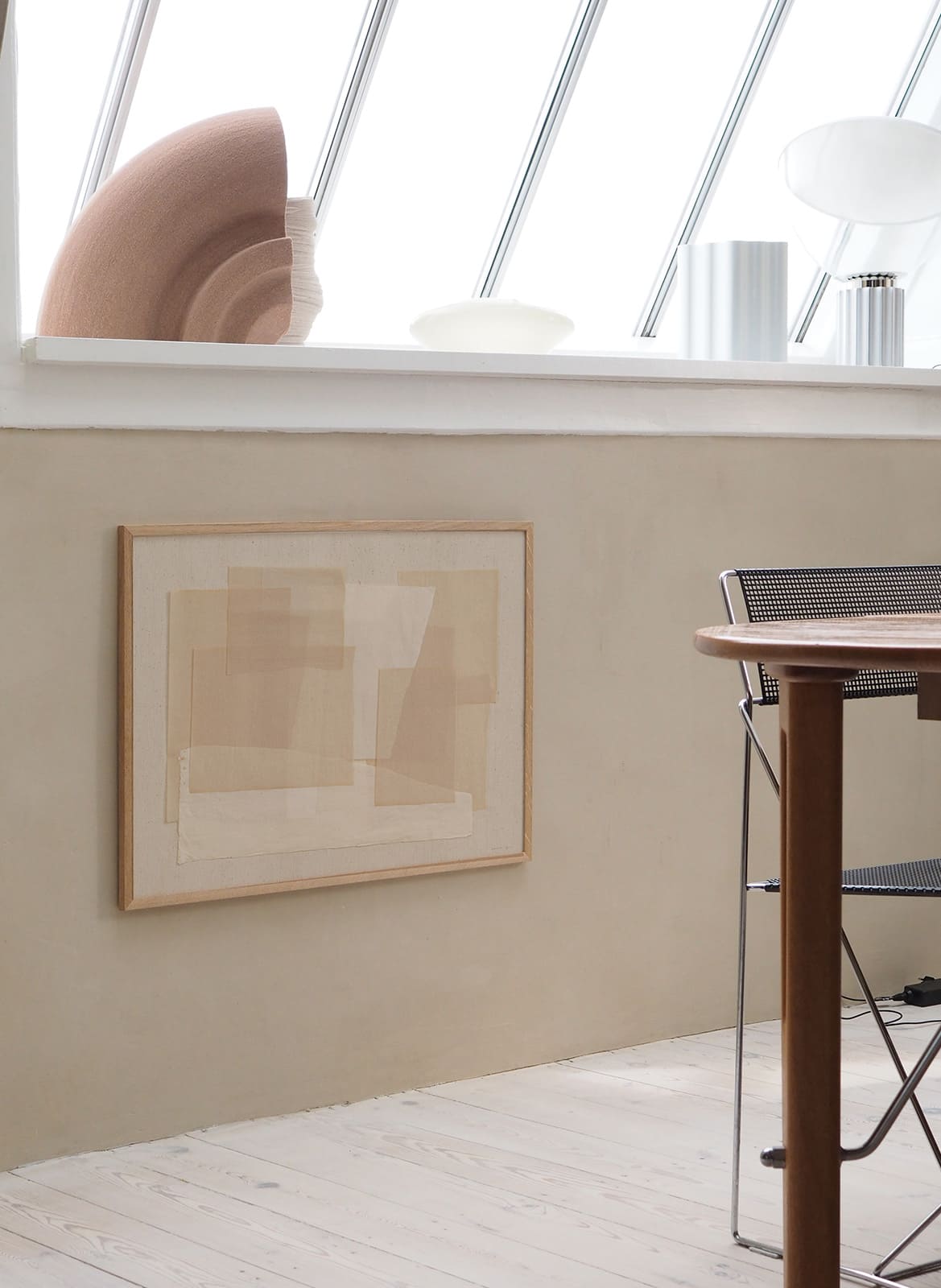 Beige minimalistic poster hanging behind a kitchen table by atelier cph