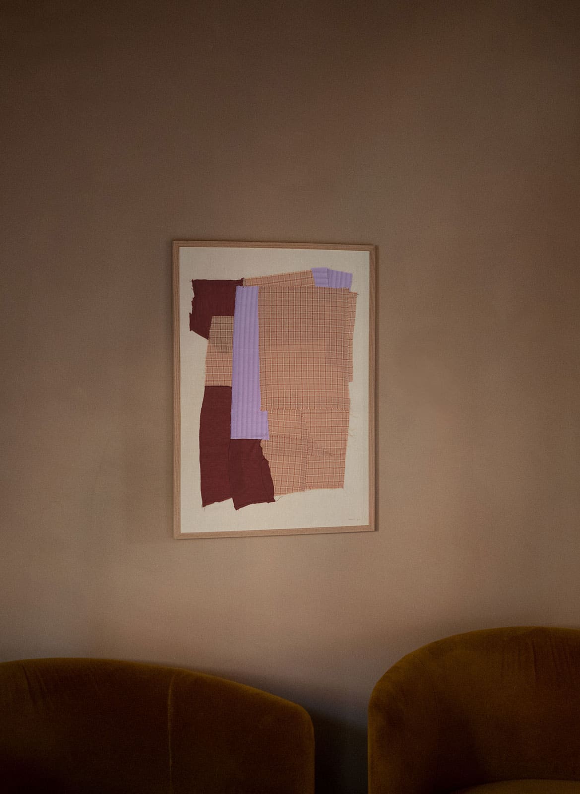 Framed colourful poster hanging above a couch by Atelier Cph