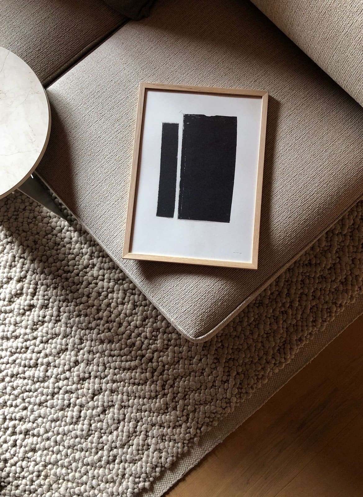 Framed black and white poster laying on a couch by Atelier Cph