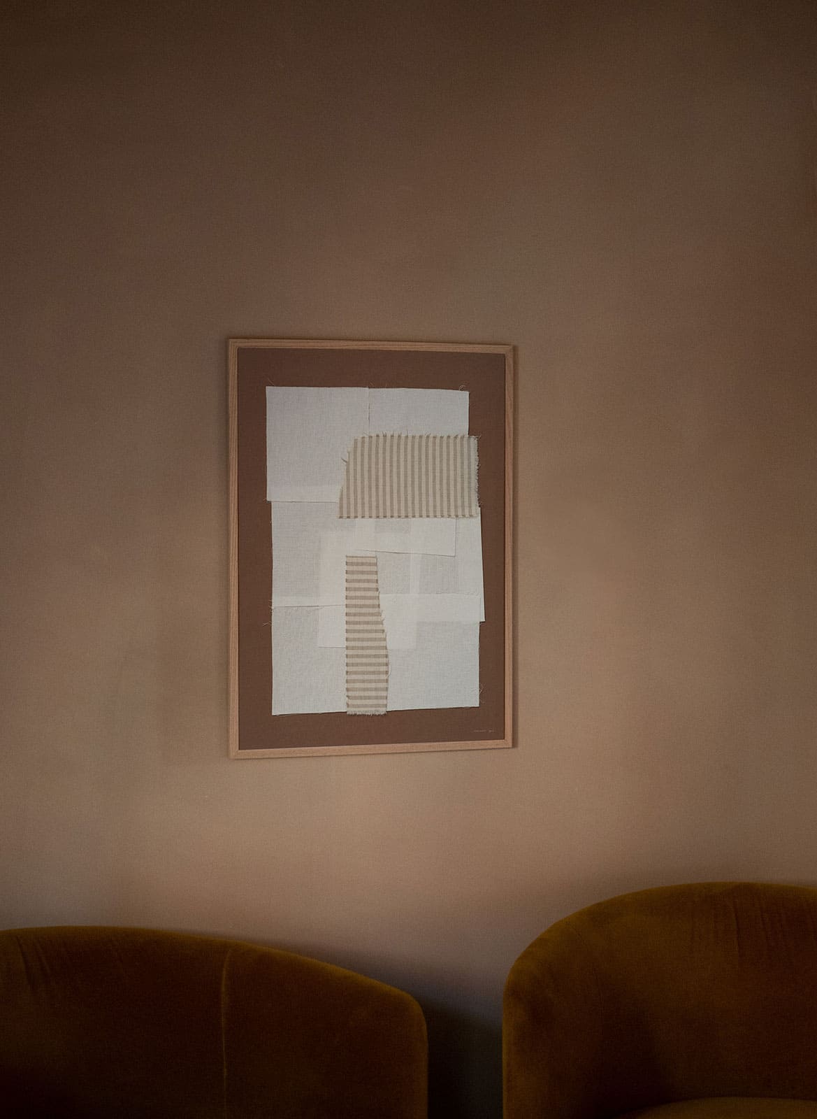 Framed abstract poster hanging above a couch by Atelier Cph