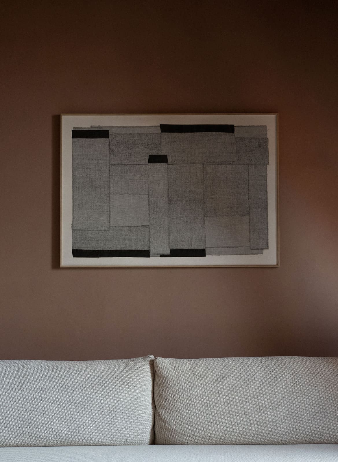Framed grey poster hanging above a couch by Atelier Cph