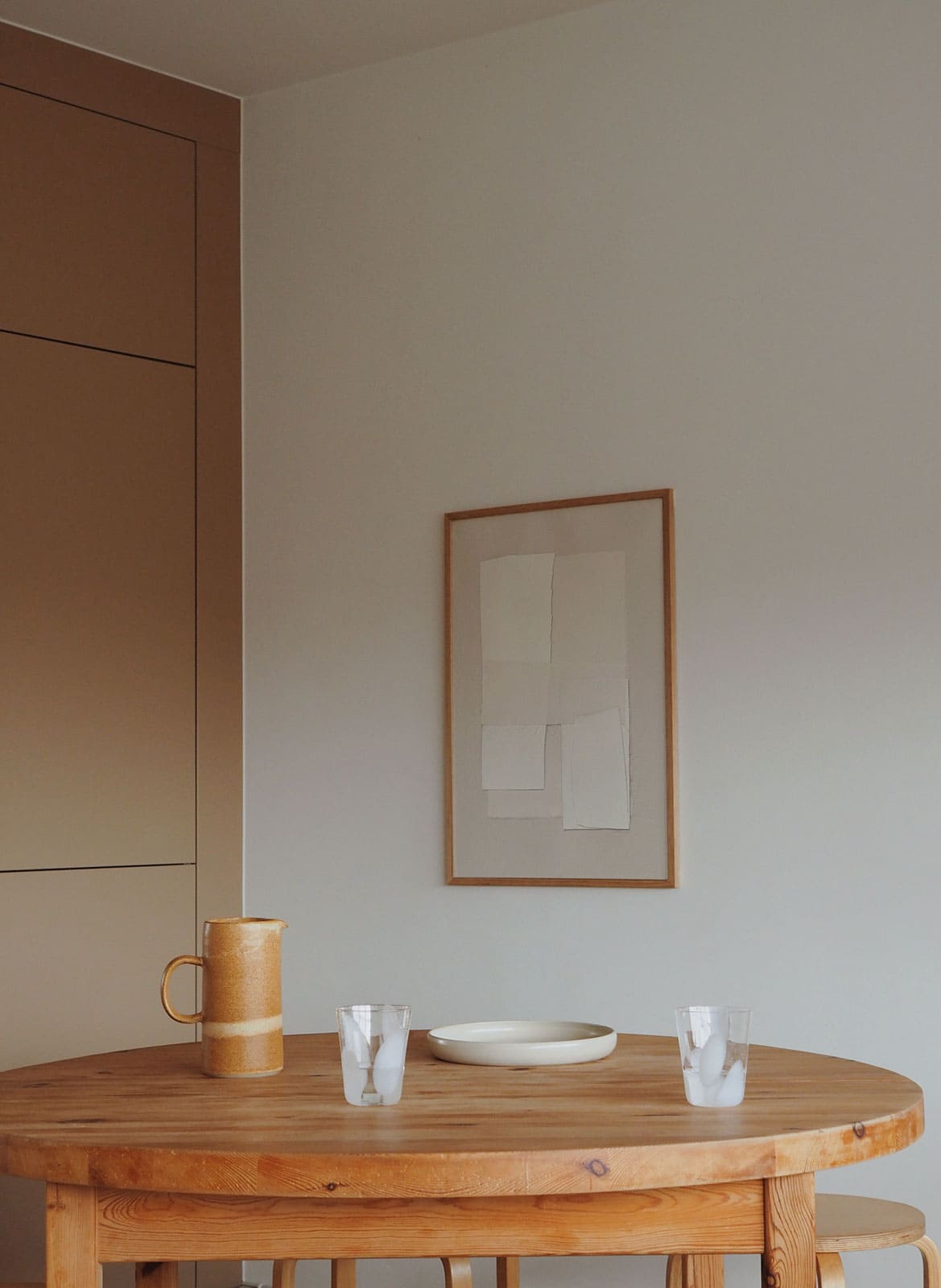 Framed white poster hanging above dining table by Atelier Cph