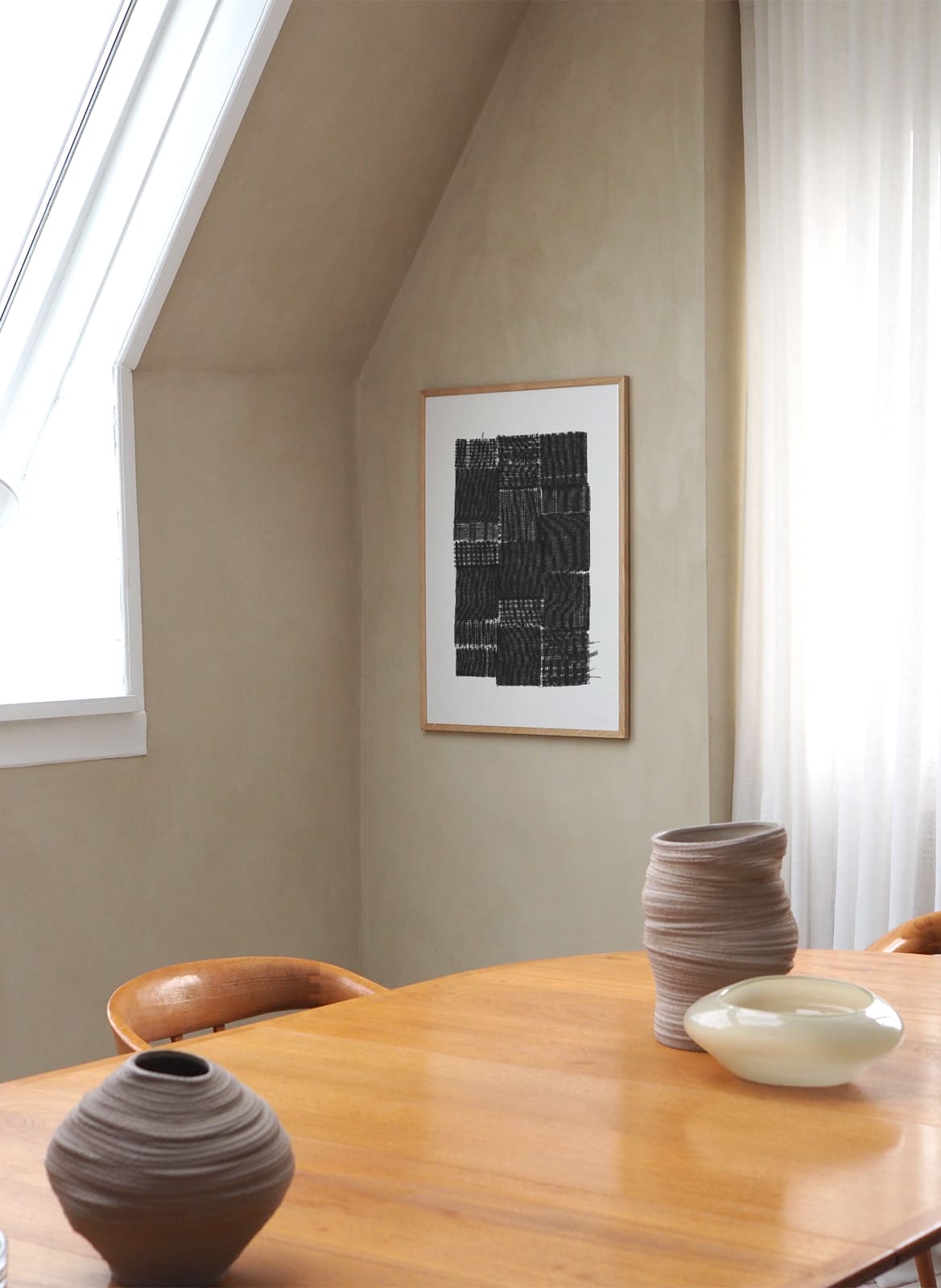 Framed black poster hanging above dining table by Atelier Cph