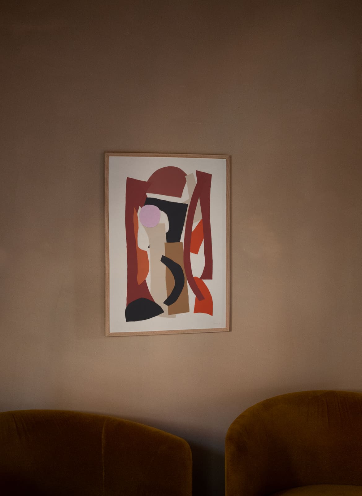 Framed colorful poster hanging above a couch by Atelier Cph