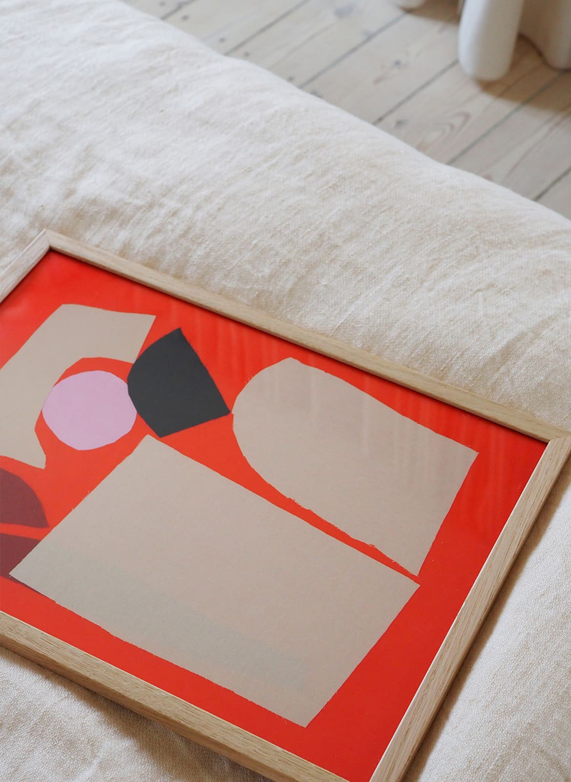 Framed colorful poster laying on a bed by Atelier Cph