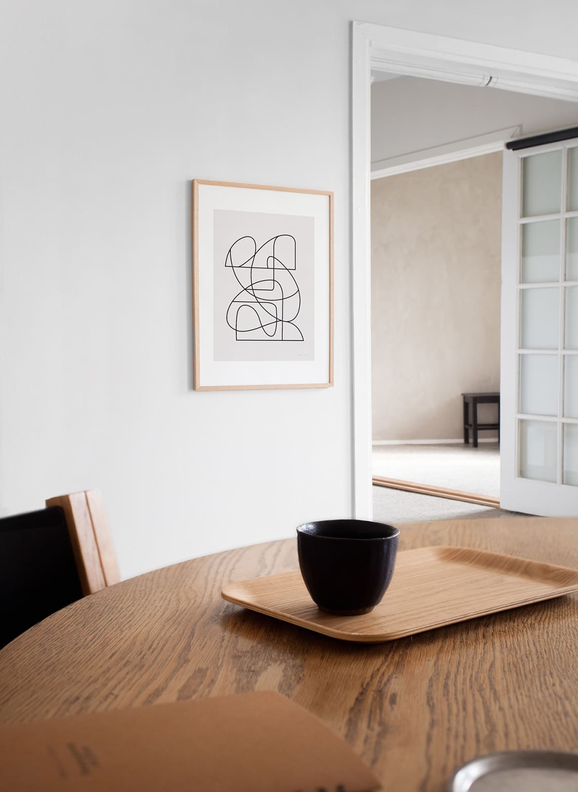 Framed minimalistic posters hanging above a desk/table by Atelier Cph