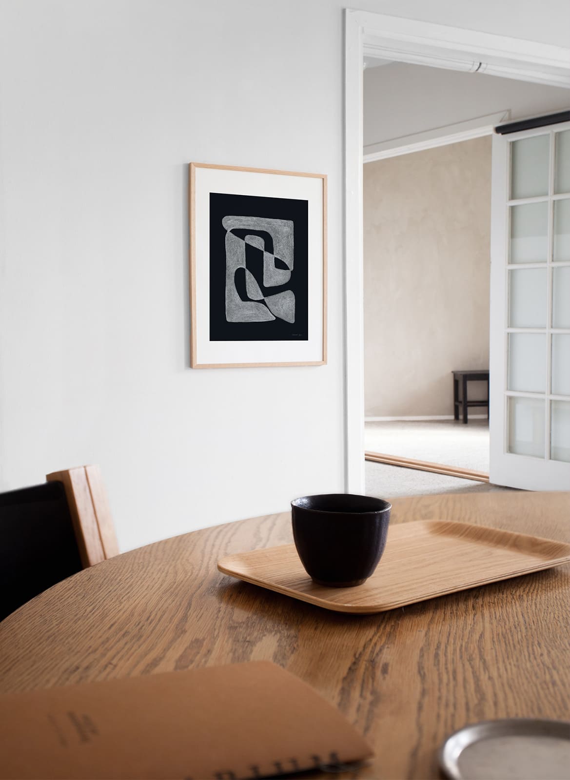 Framed black and white poster hanging above dining table by Atelier Cph