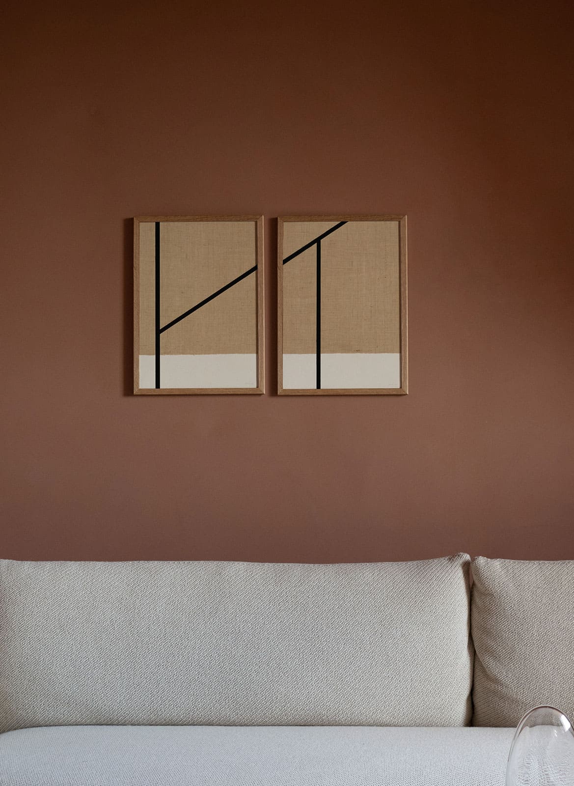 Framed minimalistic sandy posters with black lines hanging above a couch by atelier cph