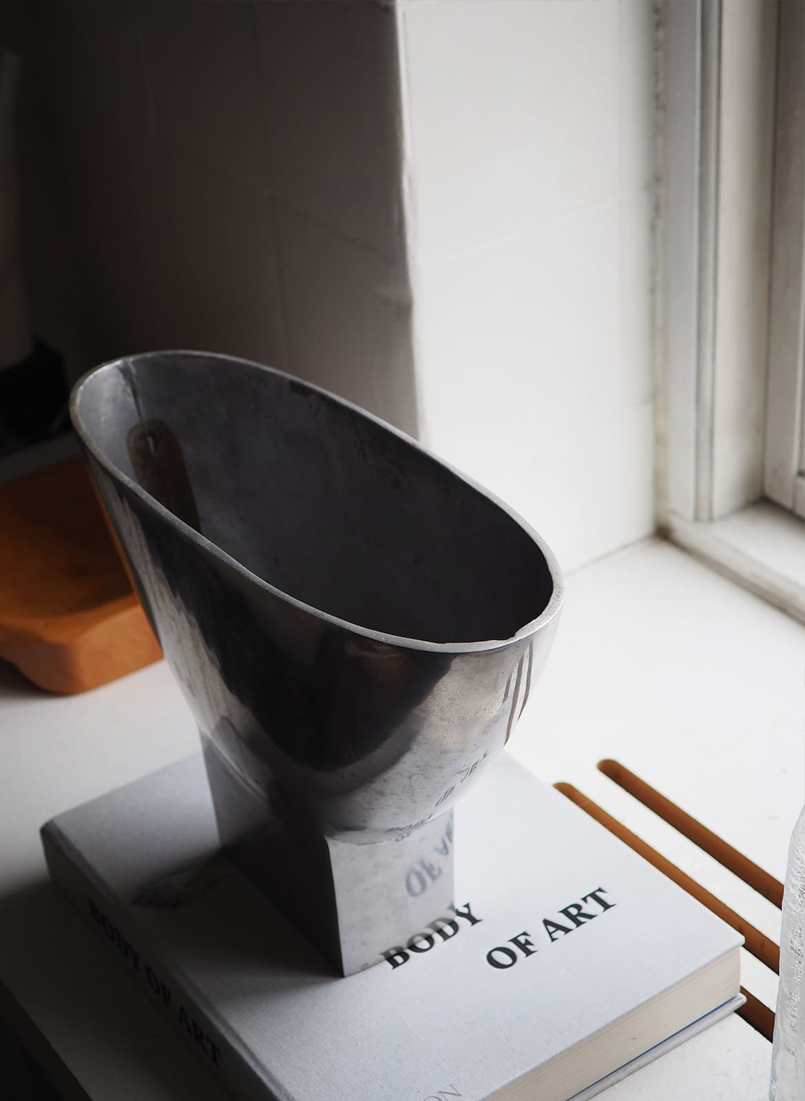 sculptural silver vase standing at a window