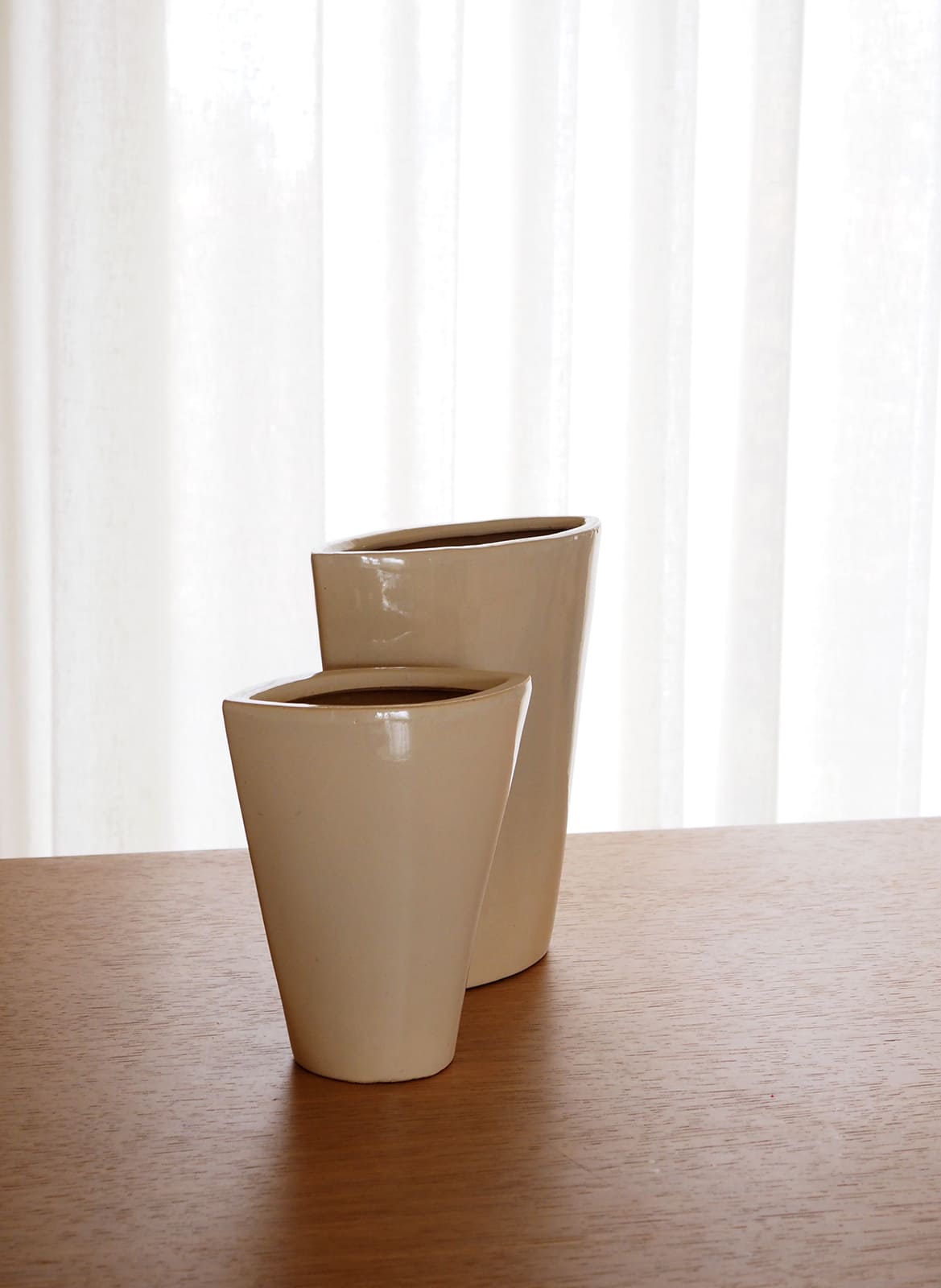 two beige vases standing on a wooden table